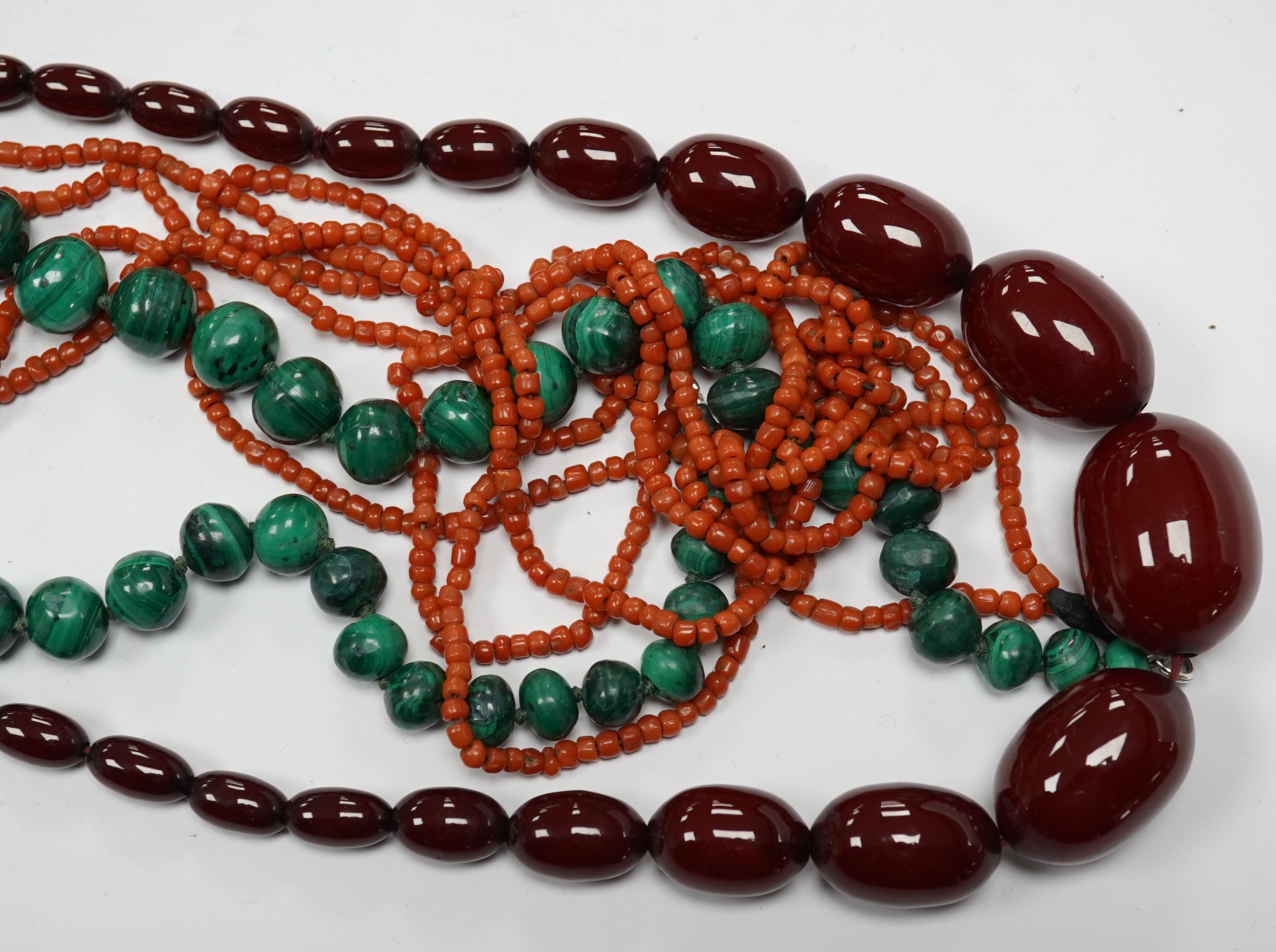 A graduated simulated cherry amber bead necklace, 43cm, gross weight 54 grams and two other necklaces including malachite. Condition - fair to good